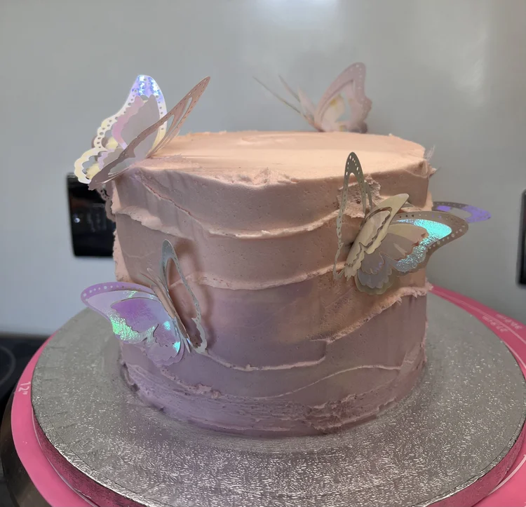 Pink cake decorated with paper butterflies